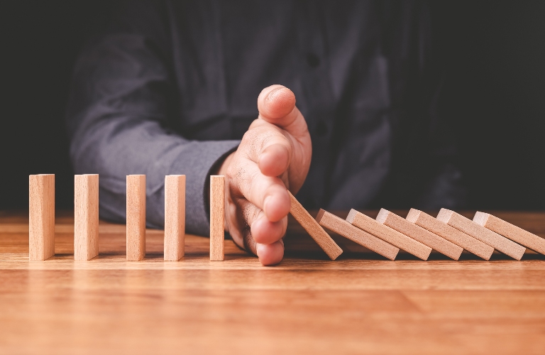man stops the crash of domino effect on the table