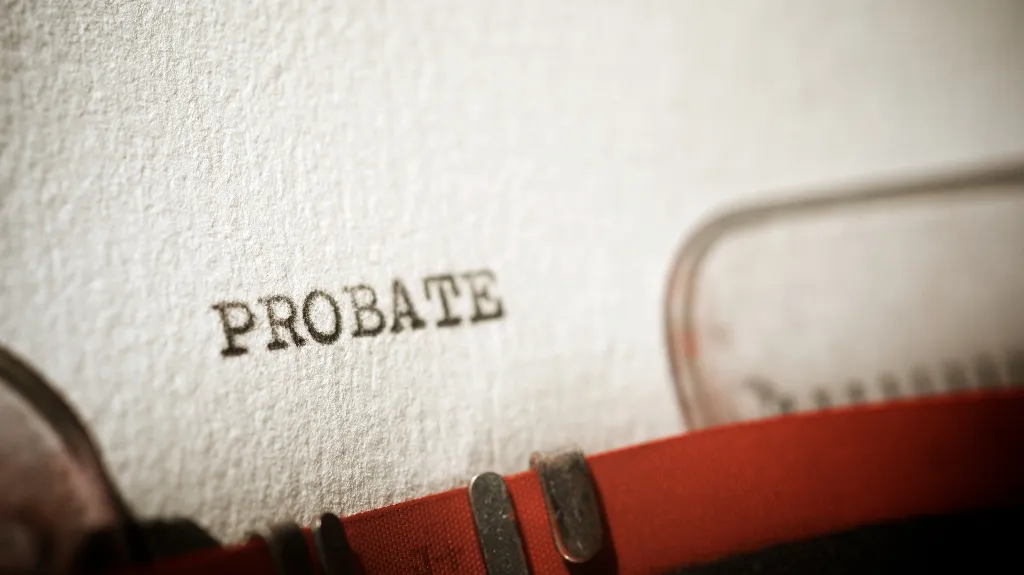 Close-up of a typewriter typing the word "PROBATE" on textured white paper.